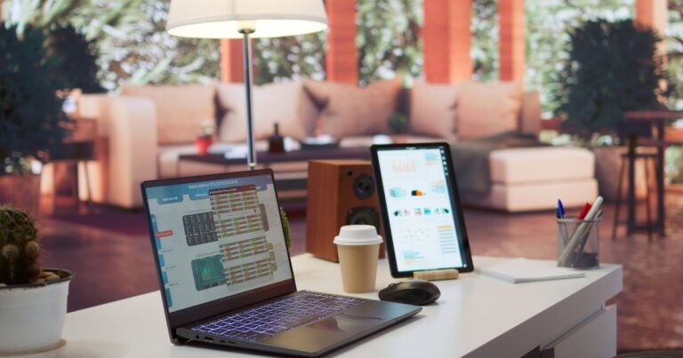 Moderner Büroarbeitsplatz mit Laptop und Tablet auf einem hellen Schreibtisch, daneben Kaffeebecher, Maus und Stifte; im Hintergrund ein ruhiger, wohnlich gestalteter Raum mit warmem Licht und Pflanzen.