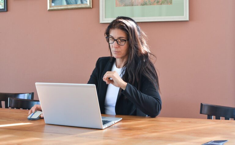 Frau sitzt am Tisch mit Laptop