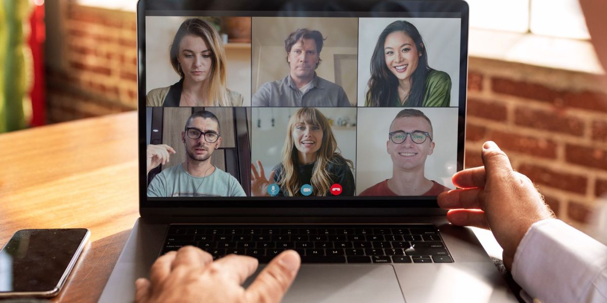 Laptop Bildschirm mit einer Videokonferenz mit Kollegen und Händen auf der Tastatur