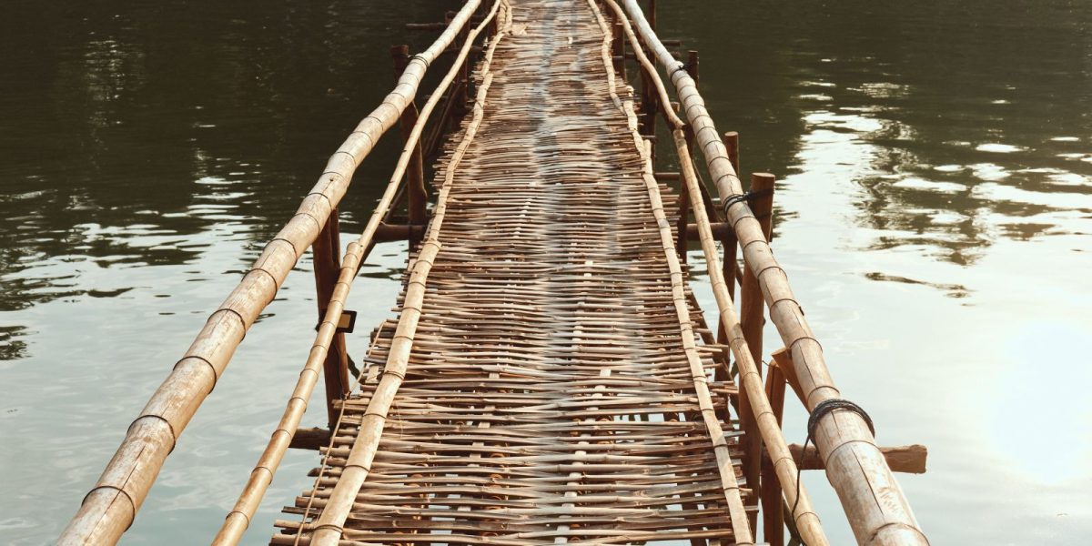 unsichere Bambus Holzbrücke führt über Wasser