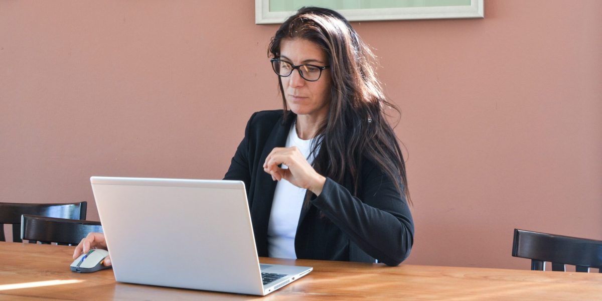 Frau sitzt am Tisch mit Laptop